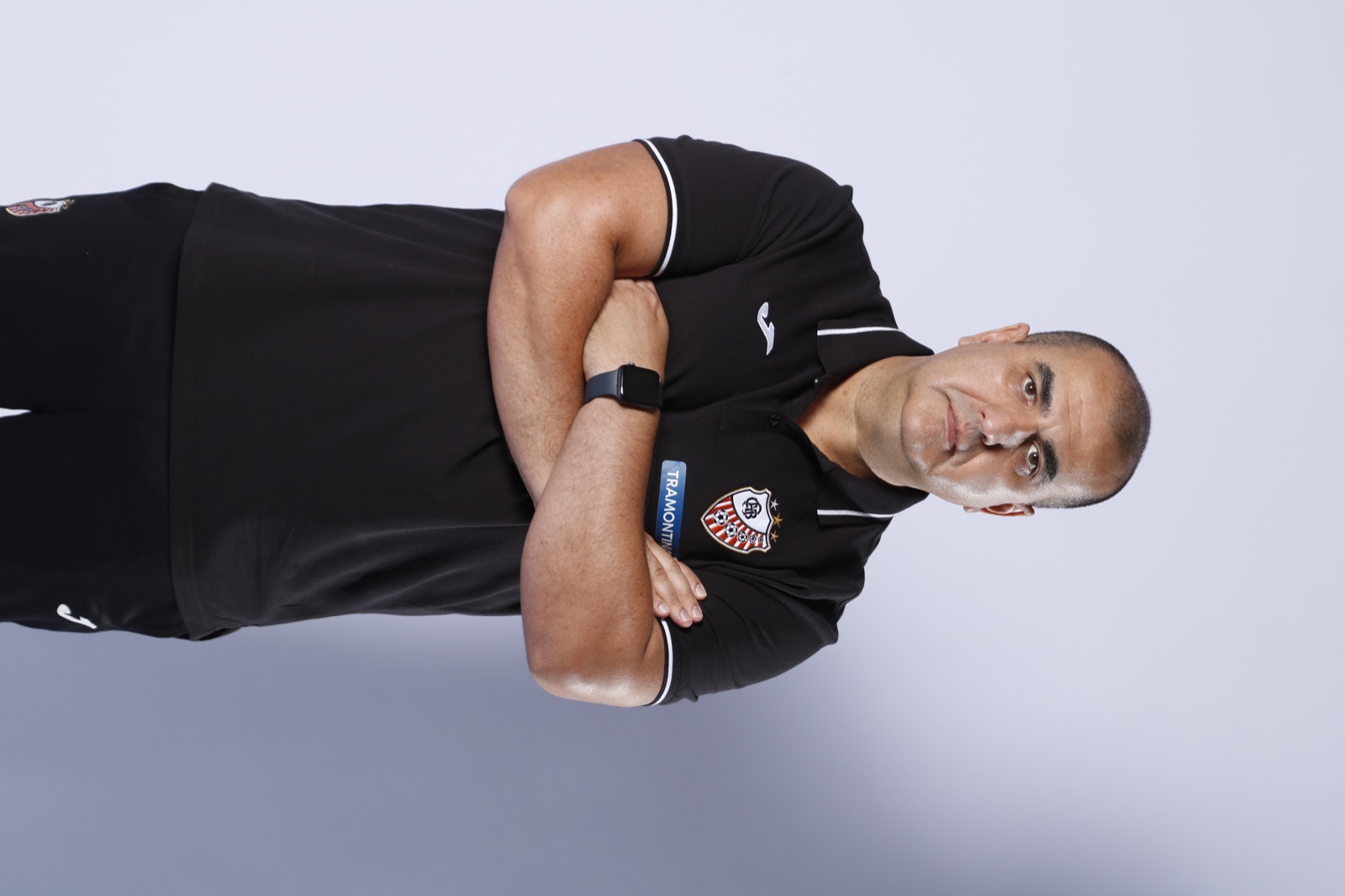 Professor Guaíba de braços cruzados em uniforme de treinador