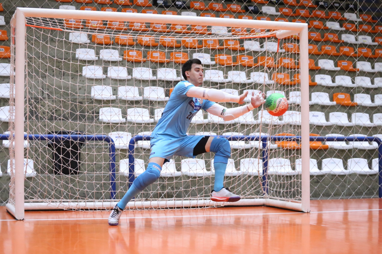 Goleiro de futsal defendendo uma bola durante treinamento